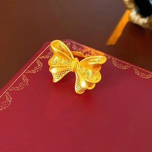 Macro shot of 18K gold bow-shaped hollow ring with a matte texture on red leather box