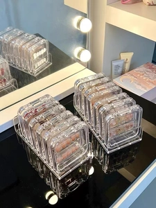 Close-up of clear acrylic display rack organizing multiple small makeup eyeshadow palettes
