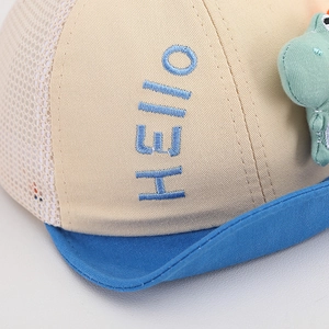Close-up of baby sun hat with 3D Hello embroidery and cute green plush dinosaur