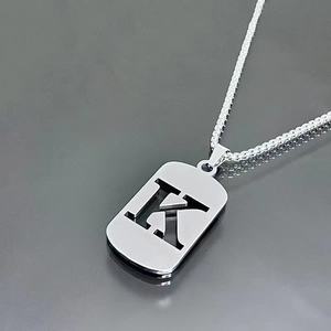Macro shot of silver hollow letter K dog tag pendant on a titanium steel necklace chain