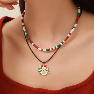 Detail of a double-layer Christmas necklace with snowman and tree enamel charms
