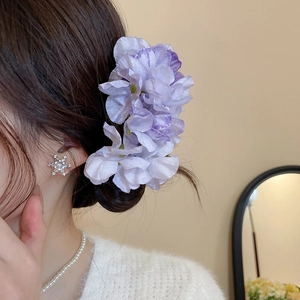 Detail view of a purple silk flower hair pin with rhinestones and elegant pearls