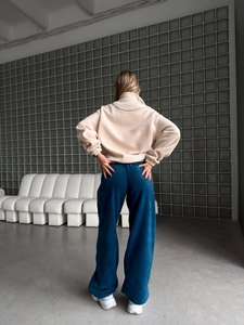 Vue arrière du sweat en polaire beige et pantalon large sarcelle pour femmes en ensemble