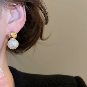 Close-up of minimalist pearl earring with gold square base worn on ear for elegant style