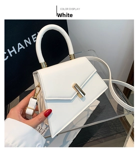 Detailed shot of white geometric handbag with gold metal clasp and leather texture