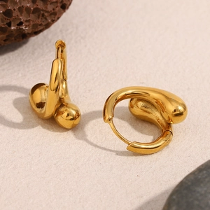 Boucles d'oreilles serpent en acier plaqué or 18K sur un présentoir en pierre naturelle