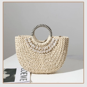 Detail of beige straw bag with natural white shells and black-and-white woven handle