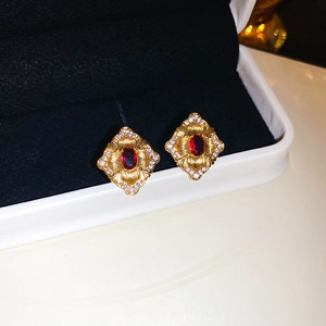 Vue macro de boucles d'oreilles vintage dorées avec gemmes rouges et pavé de zircons