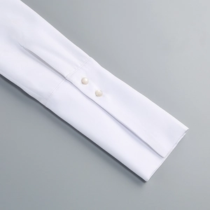 Dettaglio del polsino della camicia bianca con due bottoni perlati tondi fini