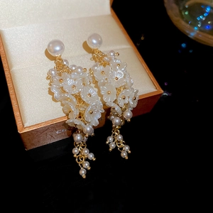 Detail of floral pearl tassel earrings with gold chain on a jewelry box edge