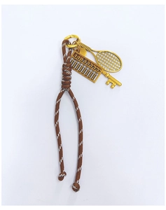 Detail showing brown braided cord with gold abacus and tennis racket metal pendants