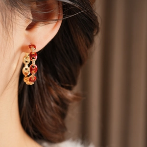 Detail of red enamel pig nose hoop earring with 18k gold plating on a model's ear