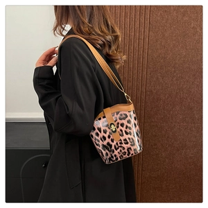 Detail showing leopard print bucket bag with brown leather strap and metal clasp on shoulder