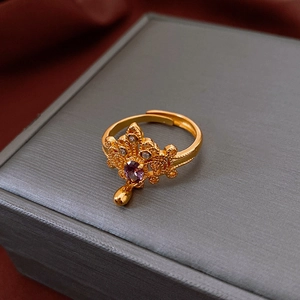 Detailed macro view of an adjustable gold ring featuring a purple stone and crystals