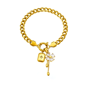 Detail of gold chain bracelet featuring star-engraved charm and clover pendant with crystal