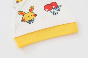 Dettaglio cappello neonato con risvolto a costine giallo e stampa con coniglio