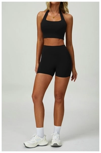 Detail view of black high-waist fitness shorts and cross-neck bra with matte texture
