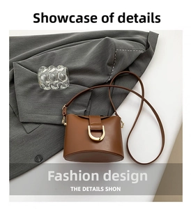 Detail view of a retro dark brown matte leather bucket bag with a golden horseshoe buckle