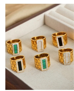 Detail of wide gold plated rings featuring honeycomb texture and rectangular stone inlay