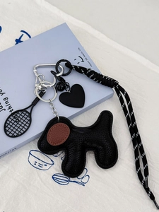 Detail of dog pendant keychain with leopard heart, tennis racket, and woven rope