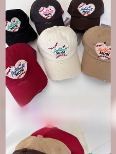 Detail of embroidered heart patch and distressed cotton fabric on colorful baseball caps