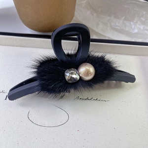 Macro detail of plush faux fur hair claw clip featuring rhinestones and a gold pearl