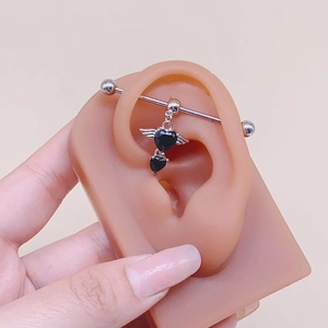 Piercing industrial con pietra a cuore nero e ali d'argento su modello di orecchio