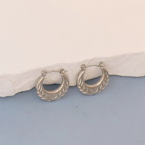 Detailed view of silver hoop earrings featuring intricate diagonal textured engravings