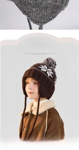 Detail of winter knit baby hat with ear flaps, fleece lining and decorative pom-poms