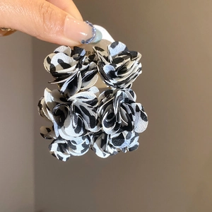 Detailed close-up of handmade black and white fabric floral square earrings held by hand