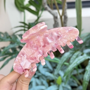 Molla per capelli in acetato rosa marmorizzato mostrata in un ambiente naturale