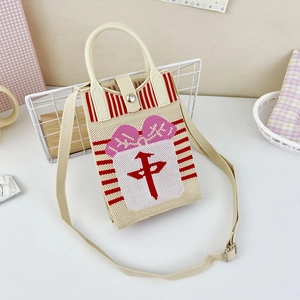 Close-up of knit crossbody bag with mahjong character and pink bow on desk