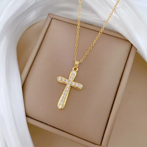 Close-up of gold cross pendant with cubic zirconia stones on silk and jewelry box