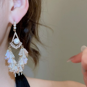 Detail of luxury crystal drop earrings with pearls and soft pink tassels on a model