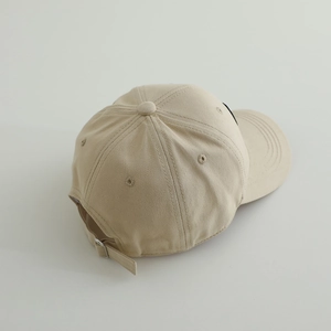 Top view of beige cotton baseball cap showing stitching details and adjustable metal buckle