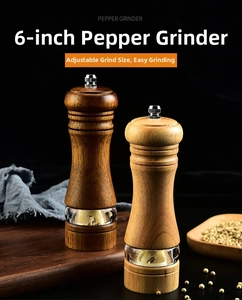 Detail view of 6-inch oak wood pepper grinders with acrylic window on black background