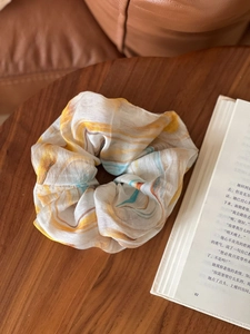 Oversized marble pattern scrunchie in orange and blue on a rustic wooden table detail