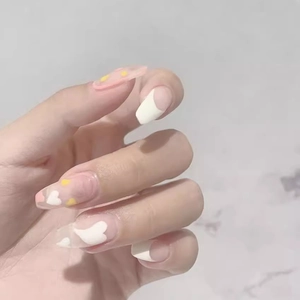 Pink and white French press-on nails with heart patterns and yellow polka dot accents