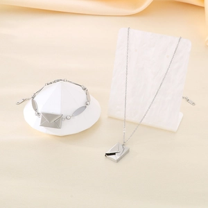 Dettaglio di collana e bracciale con ciondolo a busta d'argento su supporti eleganti