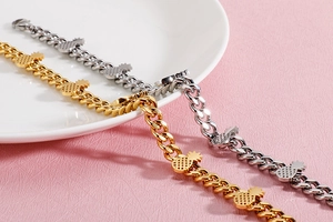 Close-up of gold and silver pineapple charm bracelets on a textured background