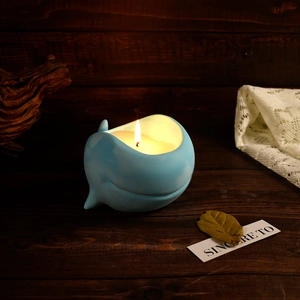 Bougie parfumée en forme de baleine bleue avec lumière chaude sur fond en bois rustique