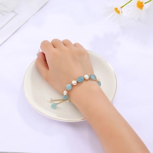 Detailed close-up of blue aventurine and freshwater pearl beaded bracelet on woman's wrist