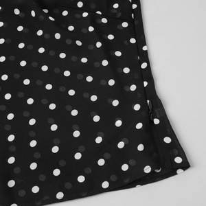 Détail de la fermeture éclair invisible sur le tissu en mousseline à pois noirs