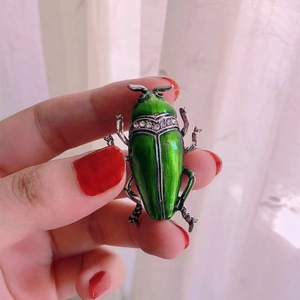 Exquisite beetle brooch with green enamel and sparkling rhinestones on hand display