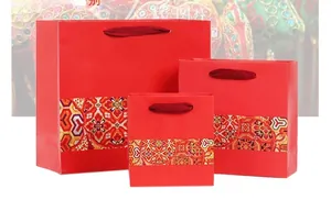 Three sizes of red ethnic style gift bags with traditional floral patterns and rope handles
