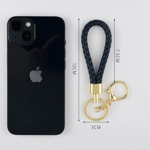 Deep blue woven leather keychain with gold metal ring and size comparison to a phone