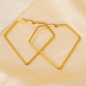 Close-up of geometric gold-plated titanium earrings on soft beige silk background