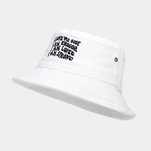 Detail of white canvas bucket hat with black motivational embroidery and metal eyelets