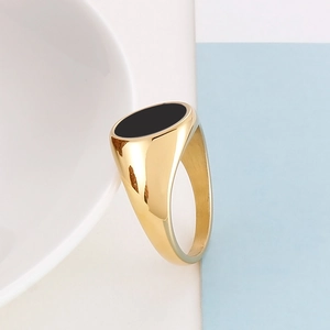 Macro view of minimalist gold stainless steel ring featuring a black oval enamel signet