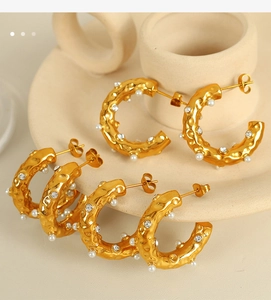 Detail of 18K gold-plated C-shaped earrings with pearls and crystals on hammered metal